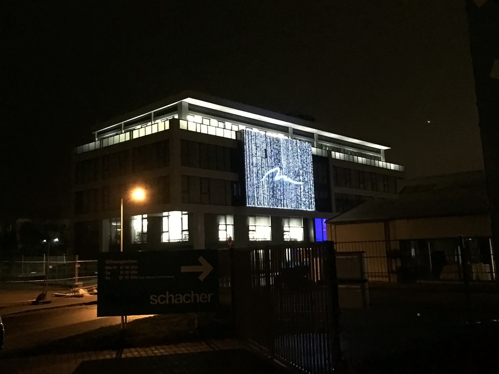 Nachtaufnahme: LED-Teppich an Bürogebäudenfassade und zusätzliche Bodenlampen auf der Dachterrasse